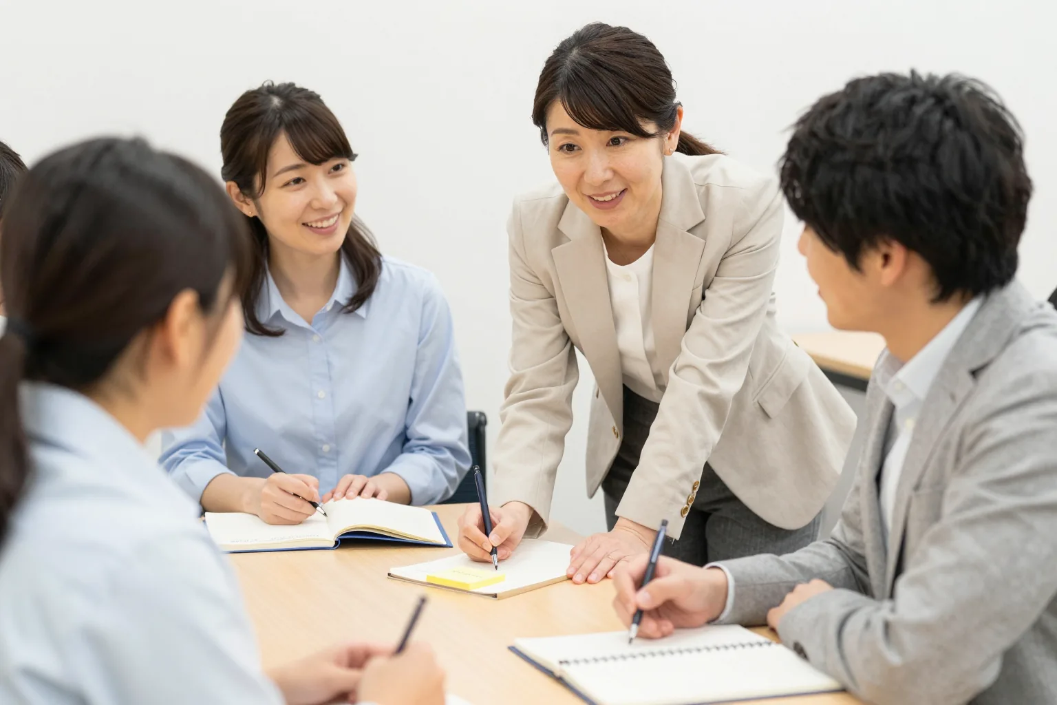 会議室のテーブルで、受講者のそばにかがんで話を聞く木下早苗