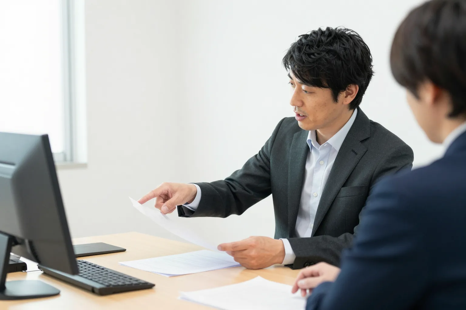 打ち合わせの机で、宮田が書類を指さしながら社長と話している